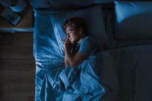 young man sleeping peacefully in darkened room