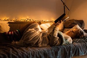 girl reading in bed with cosy lighting
