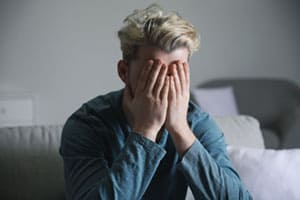 Young male head in hands, poor mental health